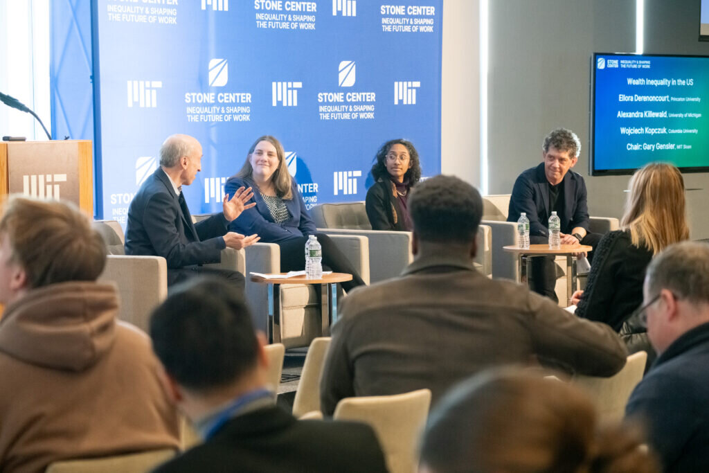 Four panelists sit in armchairs onstage in front of a blue Stone Center banner.